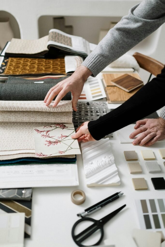 Two designers explore fabric samples and color swatches on a creative, well-organized workspace table.