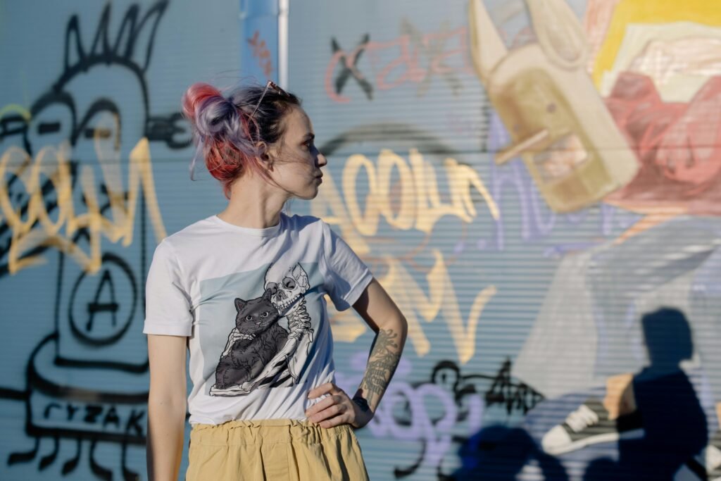 A young woman with vibrant hair poses confidently outdoors.