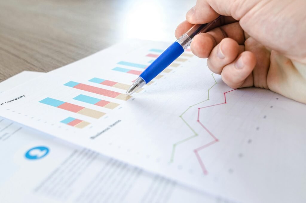 A hand holding a pen pointing at a chart.