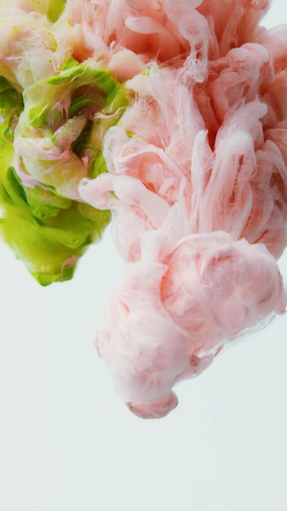 Soft pink and green ink swirling underwater.